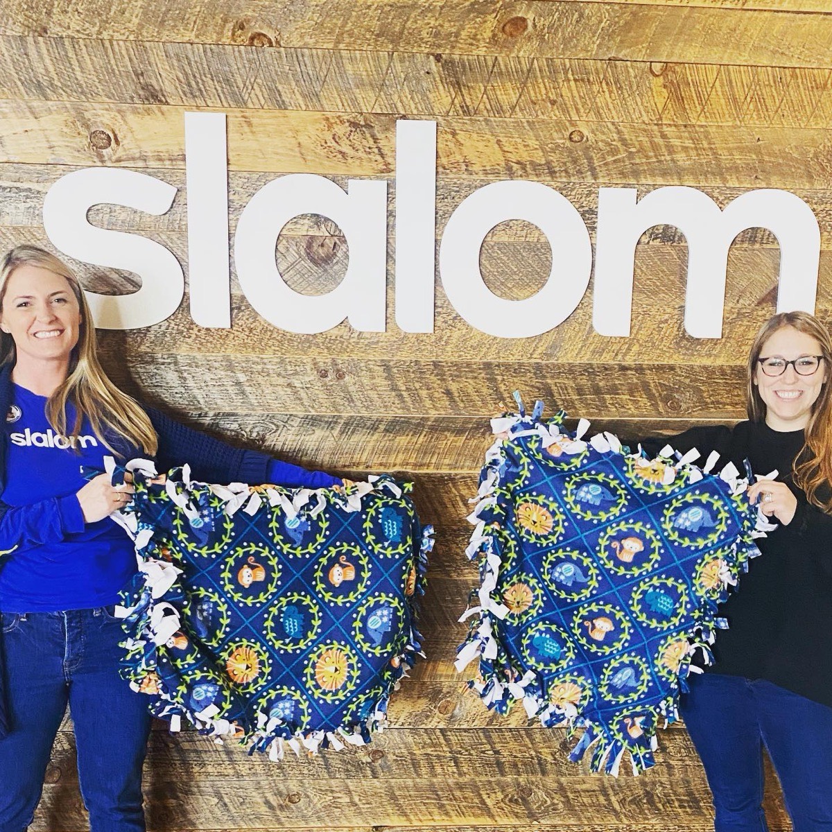 Two volunteers holding up finished fleece blankets